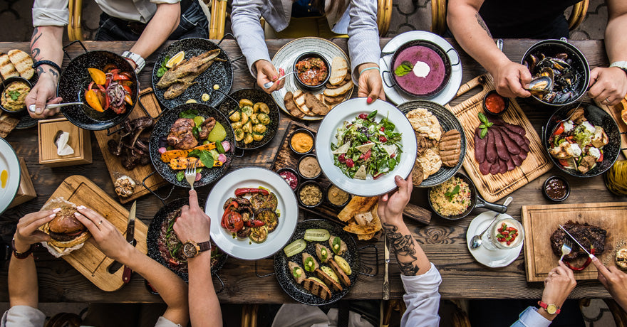 Long table with a lot of food being pass around, top view